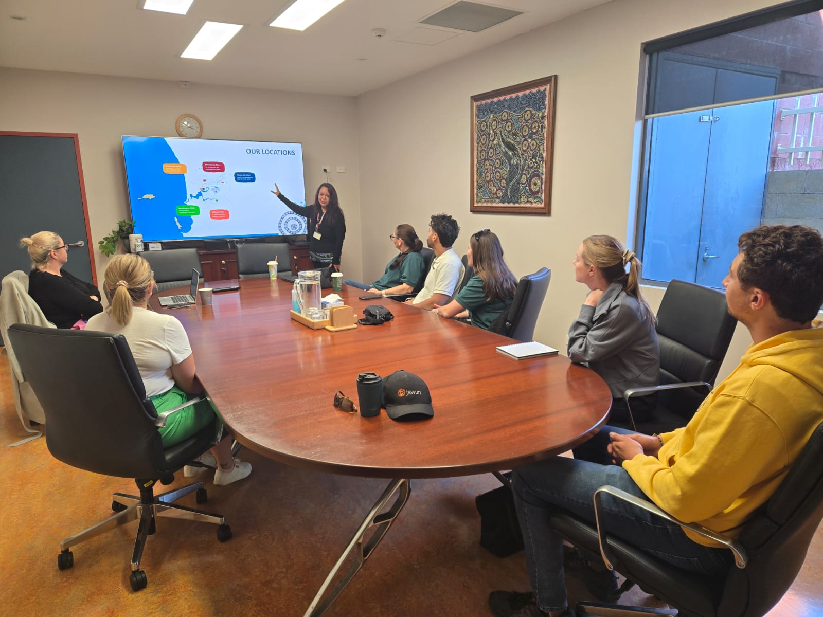 A board room at Derbarl Yerrigan with several people at the table listening to a presentation talk.